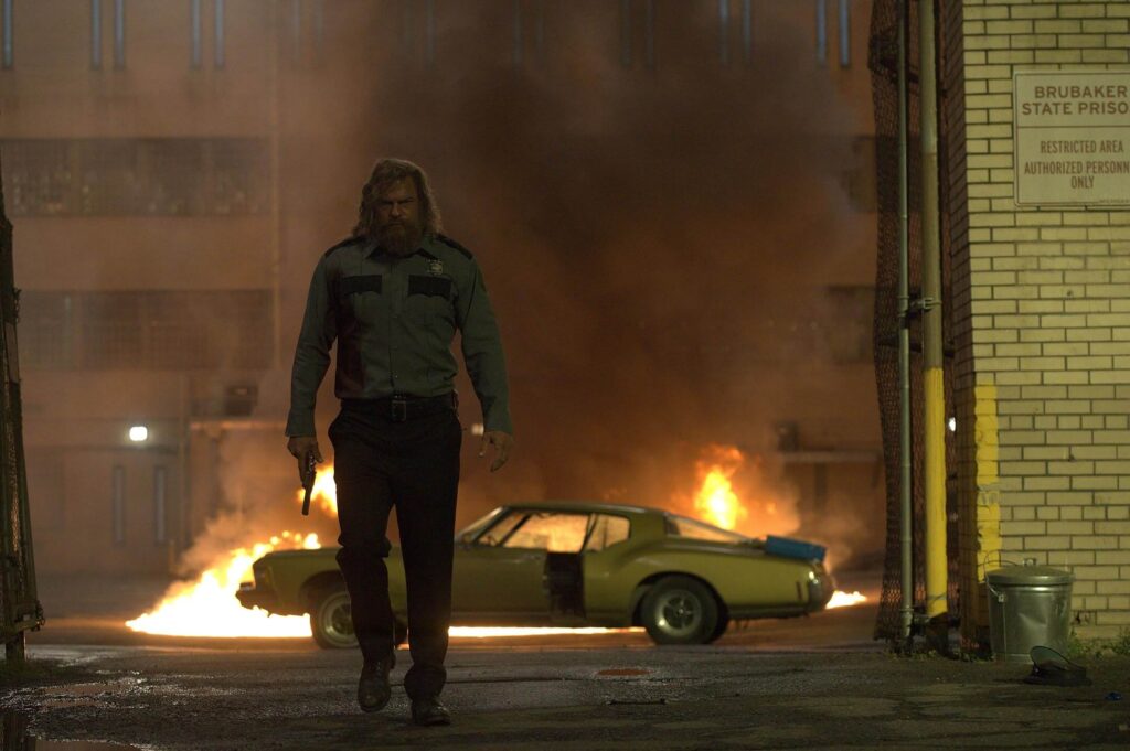 Ritchson walks away from a burning car outside Brubaker State Prison in "Motor City." - The Latino Slant