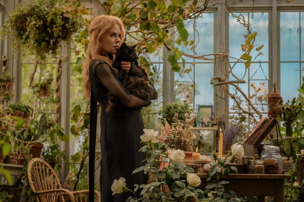 Gillian holds her familiar close inside a greenhouse full of magic in "Practical Magic 2." - The Latino Slant