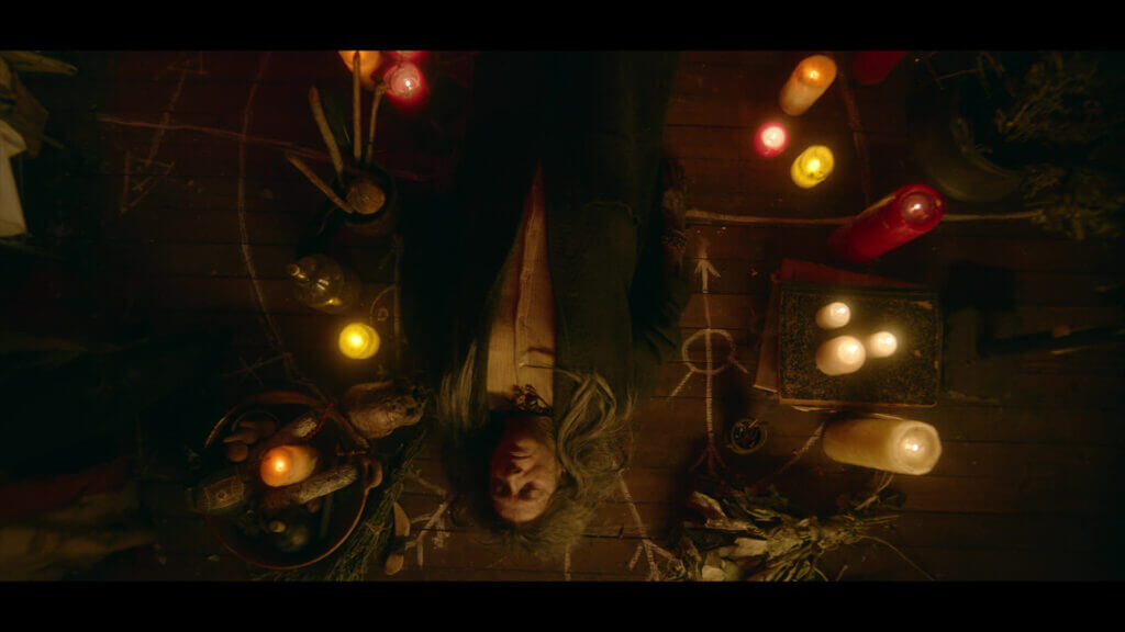 Griselda (Constanza Gutierrez) lies surrounded by candles and ritual markings in "Rosario." - The Latino Slant