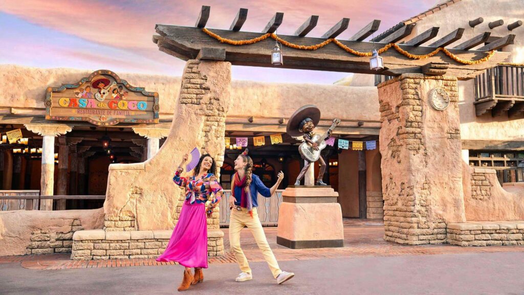 Guests dance outside Casa de Coco - Restaurante de Familia, next to a statue of Miguel from Coco, at Disneyland Paris. - The Latino Slant