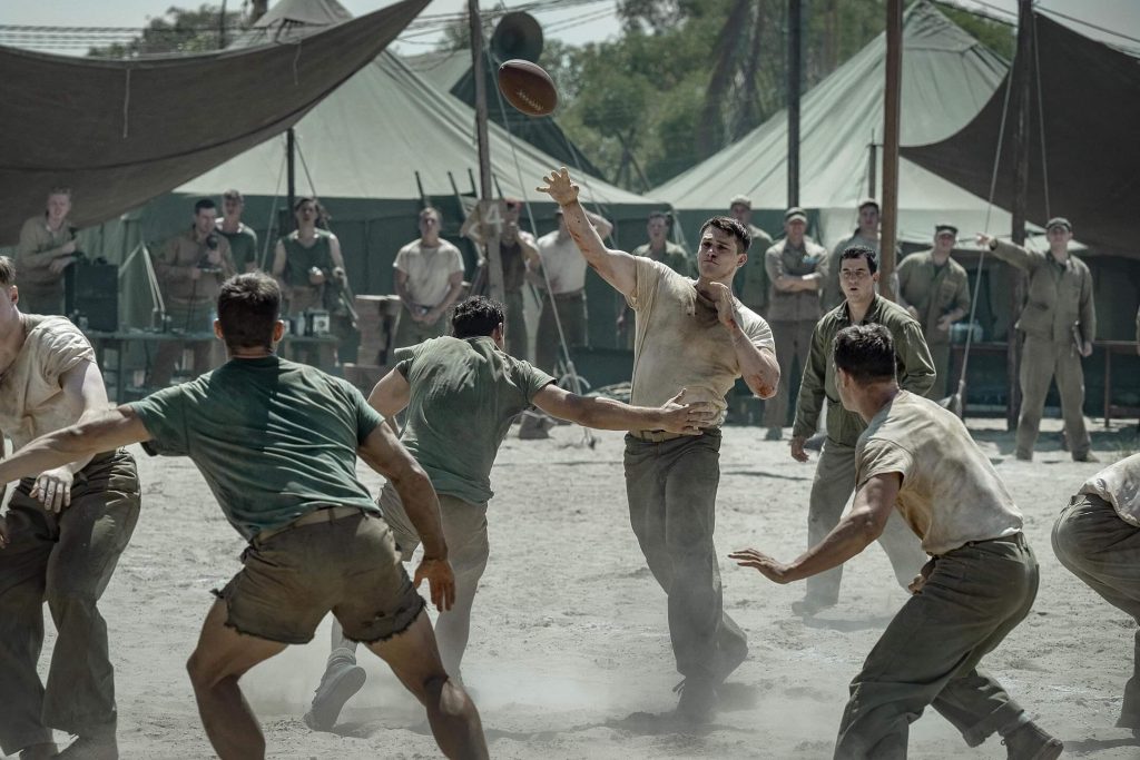 John launches a pass as fellow servicemen look on in “The Mosquito Bowl.” - The Latino Slant
